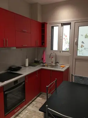 a kitchen with red cabinets and a sink and a table at Acropolis brand new 1min from metro! in Athens