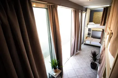 a room with a window and a bedroom with plants at Bedway Athens Hostel in Athens