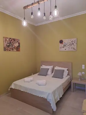 a bedroom with a large bed with white sheets at Vicky's place,near Athens airport in Koropíon