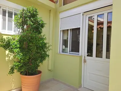 a front door of a house with a plant next to it at Vicky's place,near Athens airport in Koropíon