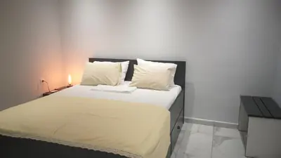 a bedroom with a large bed with white sheets and pillows at Vicky's place,near Athens airport in Koropíon