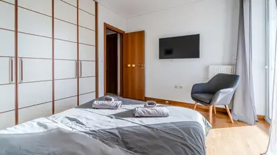 a bedroom with a bed and a chair and a television at Piraeus Bright Apt in Piraeus