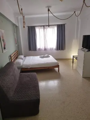 a bedroom with a bed and a couch and a window at athens.apartotel.2 in Athens