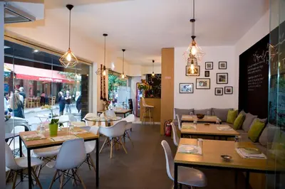 a restaurant with tables and chairs and people walking in the background at A little Taste of Home Apartments in Athens