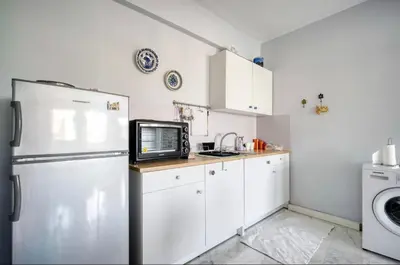 a white kitchen with a refrigerator and a microwave at A little Taste of Home Apartments in Athens