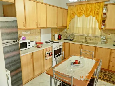 a kitchen with wooden cabinets and a table and a table and chairs at Stella's Home in Glyka Nera