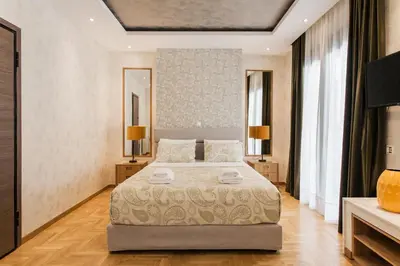 a bedroom with a large bed with two lamps and mirrors at Nicholas Point Apartments and Rooms in Athens