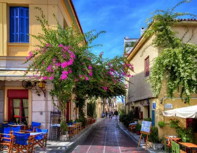 a street in a town with tables and chairs and flowers at Athens Luxury House in Athens