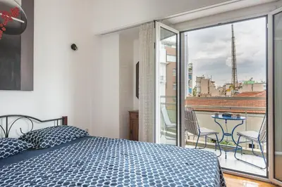 a bedroom with a bed and a balcony with a view at The Athenian Apartment in Athens