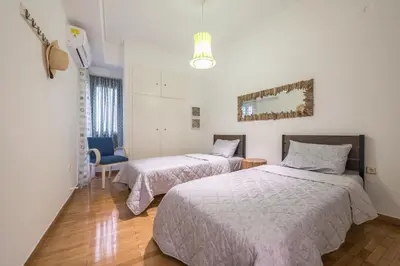 a bedroom with two beds and a blue chair at The Athenian Apartment in Athens