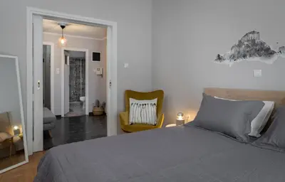 a bedroom with a bed and a yellow chair at Eleana Apartment By The Acropolis in Athens