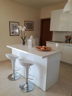 a kitchen with a white island with a plate of fruit on it at Maria's House in Athens