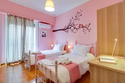 a pink bedroom with two beds and a table at Spacious Central Flat☆3min to Metro☆AC|Netflix|PC in Athens