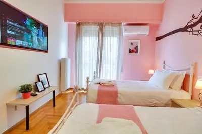 a bedroom with two beds and a flat screen tv at Spacious Central Flat☆3min to Metro☆AC|Netflix|PC in Athens