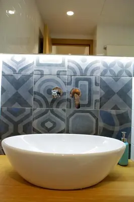 a bathroom with a white sink and a tile wall at Superior Central Apt|3min to Metro|AC|Netflix|iMac in Athens