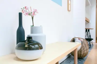 a table with a vase and a bottle on it at Superior Central Apt|3min to Metro|AC|Netflix|iMac in Athens