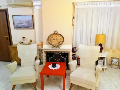 a living room with two chairs and a red table at Nana's philoxenia in Porto Rafti