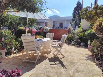 a patio with a table and chairs and an umbrella at Nana's philoxenia in Porto Rafti