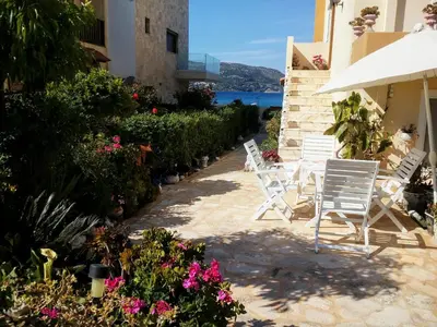 two chairs and flowers on a patio with a view of the water at Nana's philoxenia in Porto Rafti