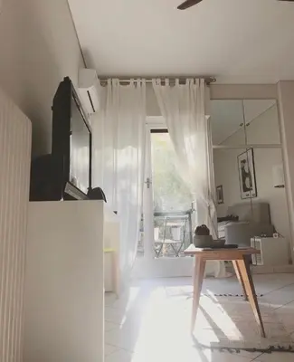 a living room with a table and a sliding glass door at Stefanias sunny Acropolis Studio on Drakou pedestrian in Athens