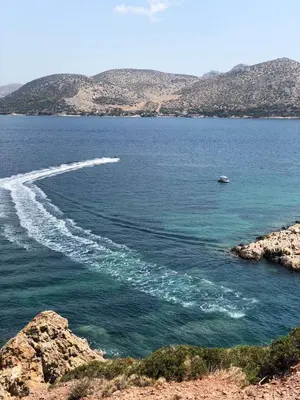 a boat in a body of water with mountains at Seaview 2nd flr. apt. next to the beach, wifi,a/c,p/c media. in Anavissos