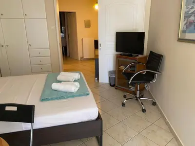 a bedroom with a bed and a chair and a television at Seaview 2nd flr. apt. next to the beach, wifi,a/c,p/c media. in Anavissos