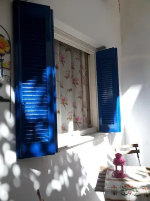 a window with blue shutters in a room with a table at Αnna's Home!!!Holidays in beautiful Athens in Athens