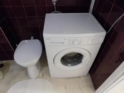 a white washing machine in a bathroom with a toilet at George's Apartment in ''Pedion Areos'' area in Athens