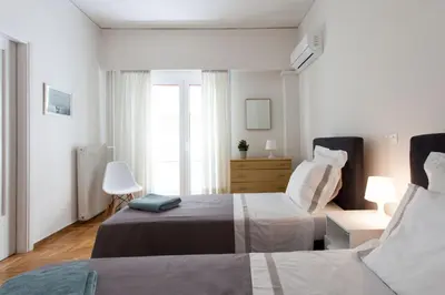 a white bedroom with two beds and a window at 2 bdrm apt for up to 6 guests next to Acropolis museum in Athens