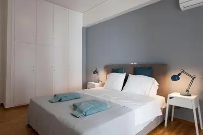 a bedroom with a large white bed with blue pillows at 2 bdrm apt for up to 6 guests next to Acropolis museum in Athens