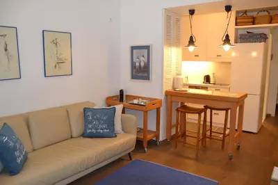 a living room with a couch and a table and a kitchen at Vouliagmeni seaside flat in Athens