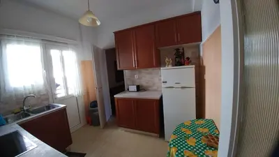a kitchen with wooden cabinets and a white refrigerator at Proteus Apartment in Athens