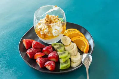 a plate of fruit with a bowl of ice cream and a plate of fruit with at Maison 66, Riviera Hotels in Athens