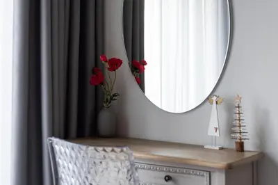 a mirror over a dresser with a vase with red flowers at Syntagma Spotlight Residence in Athens
