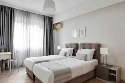 two beds in a white bedroom with a window at Syntagma Spotlight Residence in Athens
