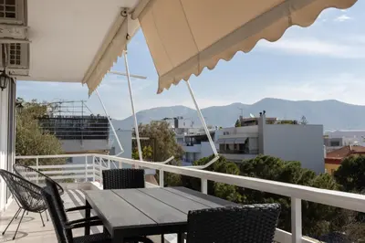 a wooden table and chairs on a balcony with mountains at Luxurious 3-Bedroom Seaside Retreat Fully Renovated in 2025 in Athens