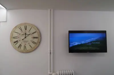 a clock on a wall next to a flat screen tv at ATHENS *BLUE GRAND SUITE *DI GIORGIO CENTRAL APARTMENT in Athens