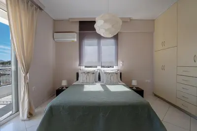 a bedroom with a green bed with a large window at Luxury Apt Near The Airport in Spáta