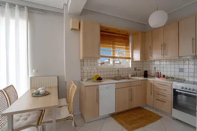 a kitchen with wooden cabinets and a table with chairs at Luxury Apt Near The Airport in Spáta
