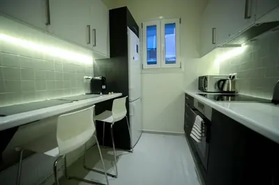 a kitchen with white counter tops and chairs in it at El Pacífico in Athens