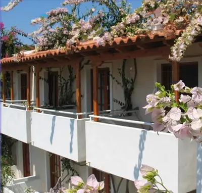 a white house with flowers on the balcony at Costantonia Holiday Apartments in Agia Marina Aegina