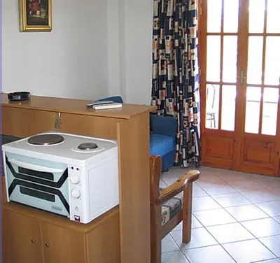 a kitchen with a microwave on a counter with a chair at Costantonia Holiday Apartments in Agia Marina Aegina