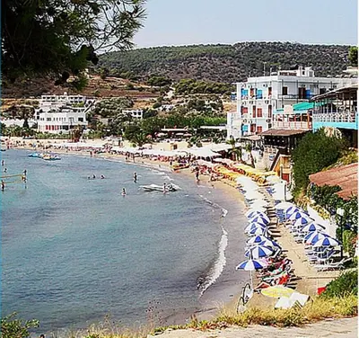 a beach with umbrellas and people in the water at Costantonia Holiday Apartments in Agia Marina Aegina