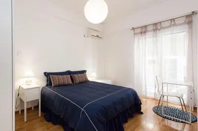 a white bedroom with a blue bed and a chair at Lovely 2 bedroom apt in Metaxourgio Center in Athens