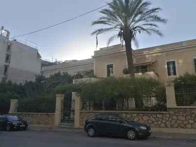 two cars parked in front of a building with a palm tree at Comfortable & Convenient Living in Athens in Athens