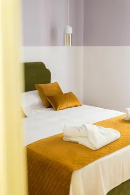 a bedroom with two beds with white sheets and gold pillows at Neratzia Rooms in Athens