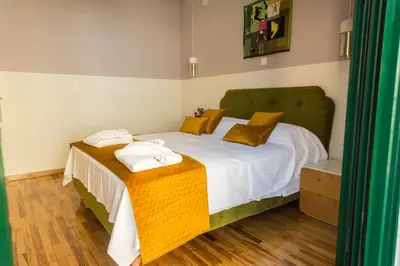 a bedroom with a bed with white sheets and yellow pillows at Neratzia Rooms in Athens