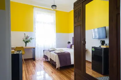 a bedroom with a bed and a yellow wall at Neratzia Rooms in Athens