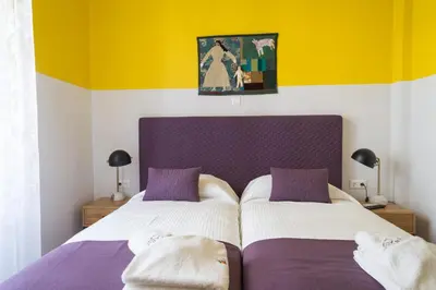 a bedroom with two beds with purple and yellow walls at Neratzia Rooms in Athens