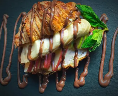 a large sandwich is covered in sauce and lettuce at Neratzia Rooms in Athens